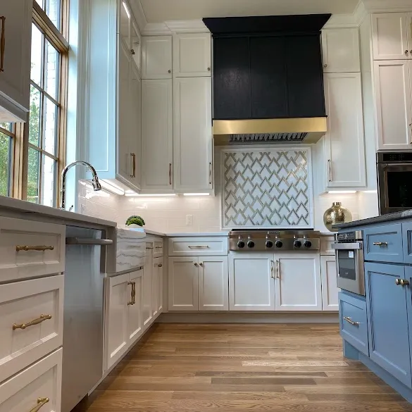 White painted kitchen cabinets with brass hardware and a blue island