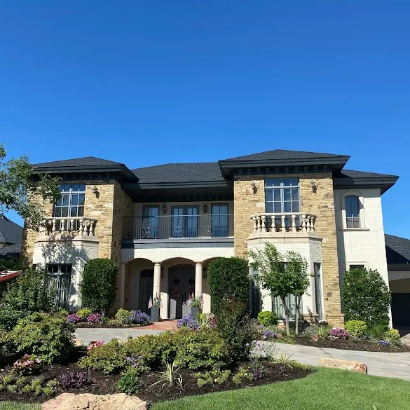 Two-story stone and brick home with freshly painted dark trim and soffits