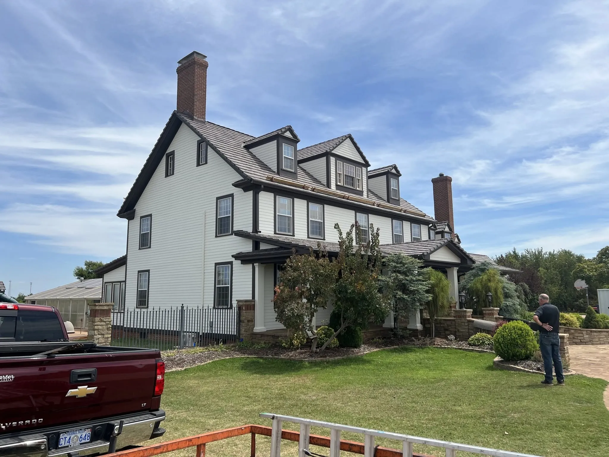 Exterior repaint of a large two-story Oklahoma home with white siding and dark trim by Supreme Finishes