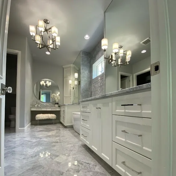 Painted primary bathroom with white cabinets and marble floors